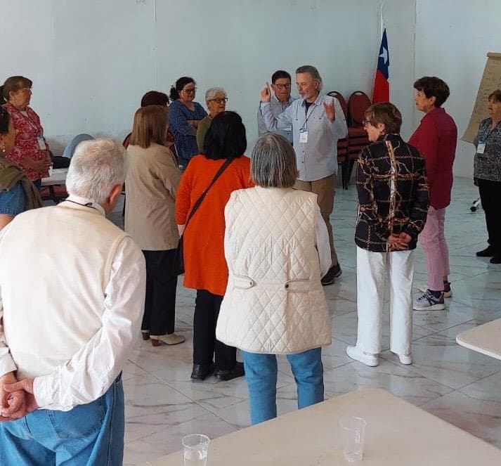 Taller presencial en círculo con adultos mayores y facilitador en el centro